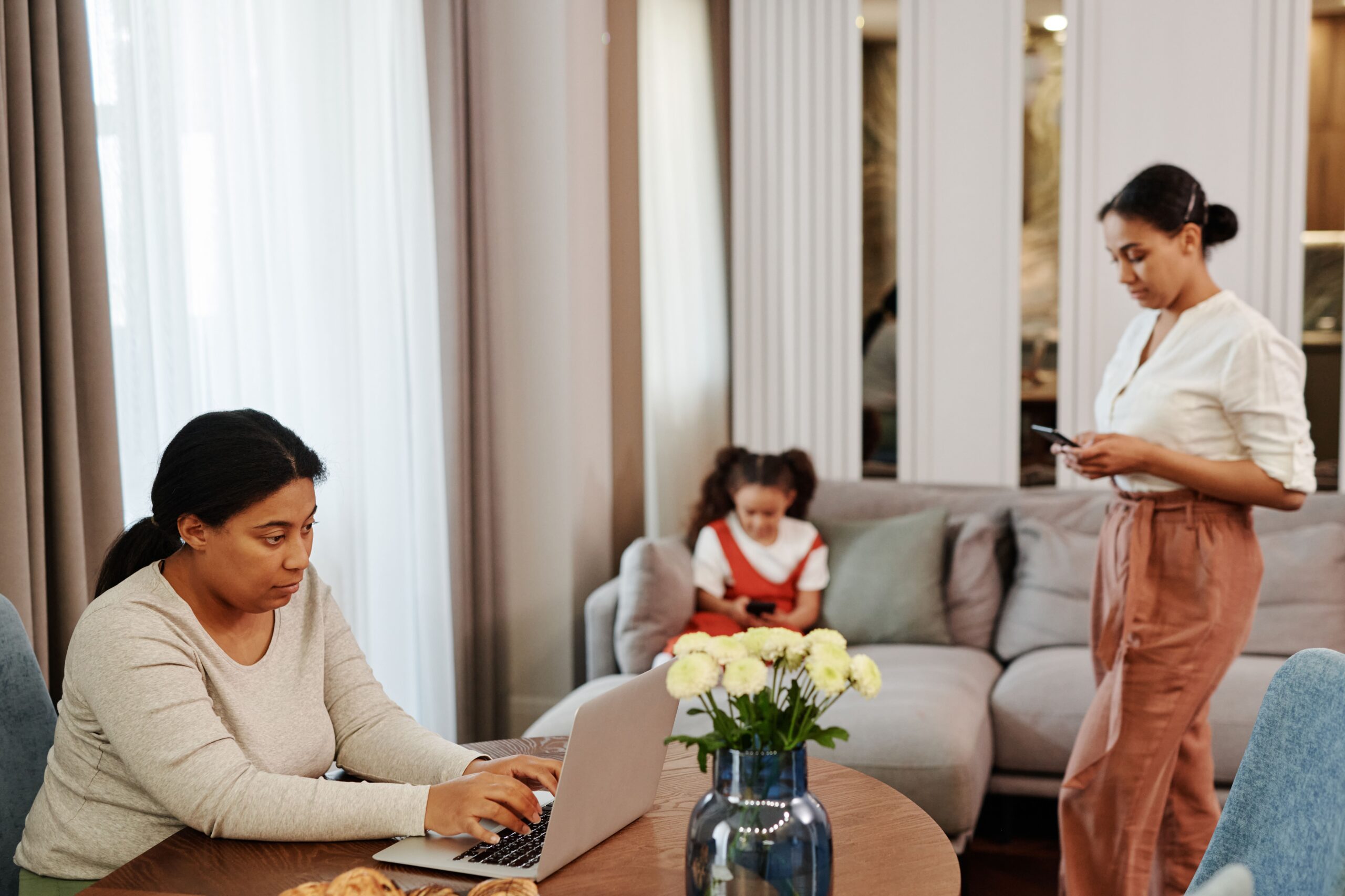 People balancing laptop work and family life in a spacious living room.